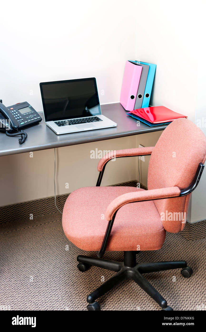 Workstation in office with swivel chair desk and laptop computer Stock