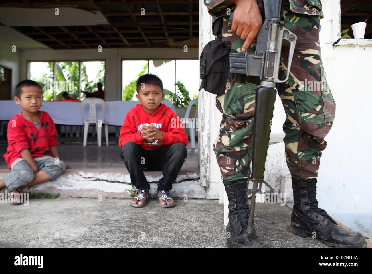 SULTAN KUDARAT, Philippines, 11th May, 2013 -- Filipino Muslim children are seen beside a soldier May 11, 2013 at the old provincial capitol in Sultan Kudarat town in the southern Philippine province of Maguindanao. The Philippine military have raised the red alert in the region as the Commission on Elections deputized them to secure on May 13, 2013 political process. In the past, Philippine elections have been marred by violence and corruption, but this year, President Benigno Aquino's government has enforced several measures in an effort to curb the bloodshed. Stock Photo