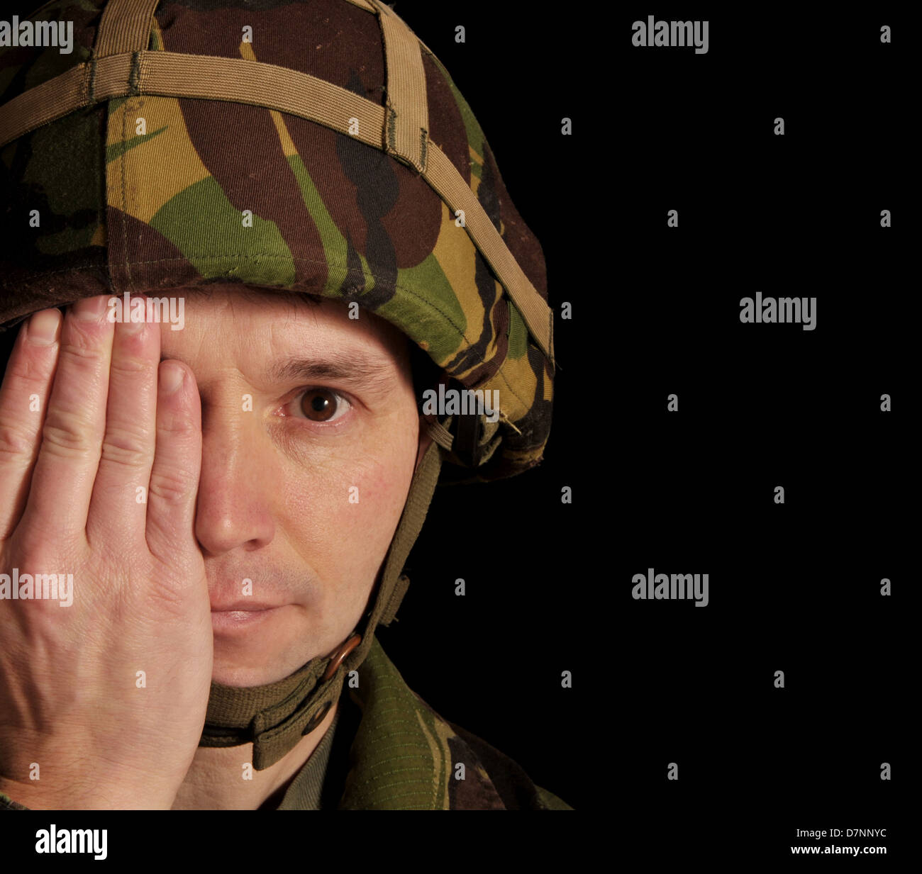 Soldier with one eye open and his hand covering the other. Studio shot