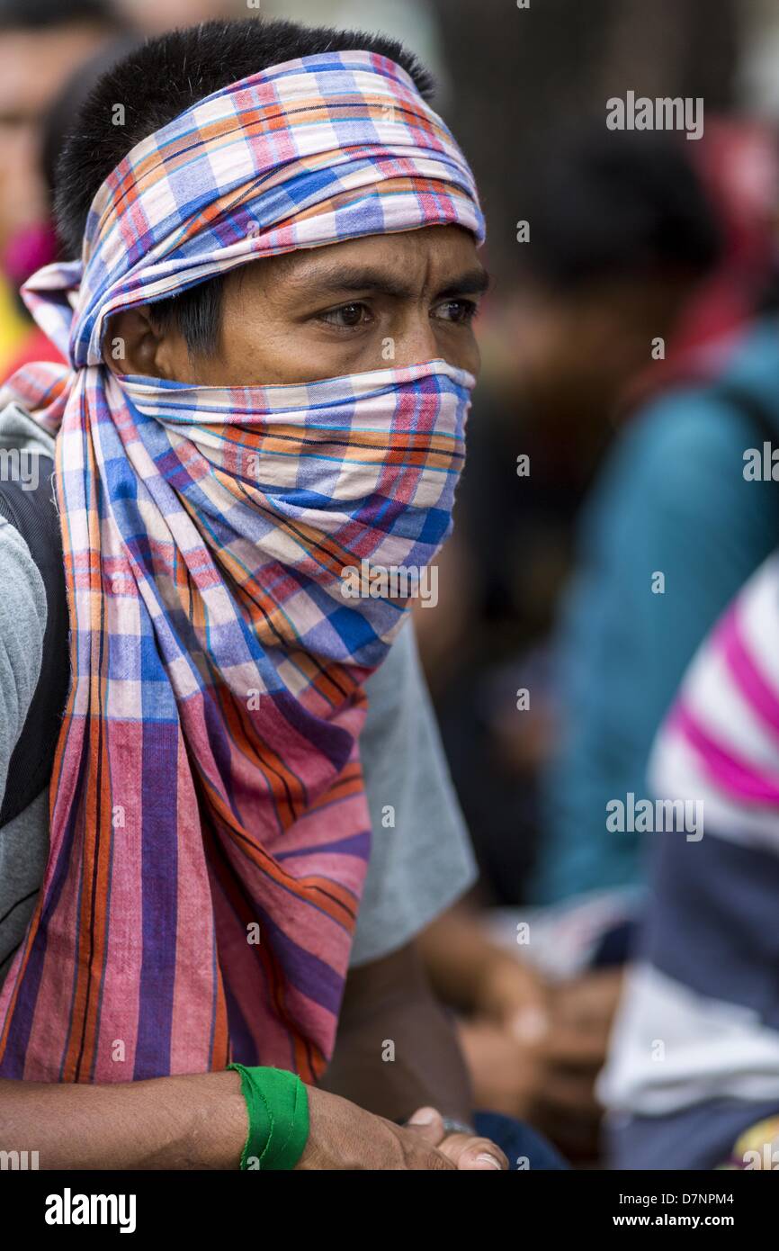 Bangkok, Thailand. May 11, 2013. A protester with a bandana over his face  sits in the road in front of Government House. Several hundred small scale  family farmers are camped out at ''