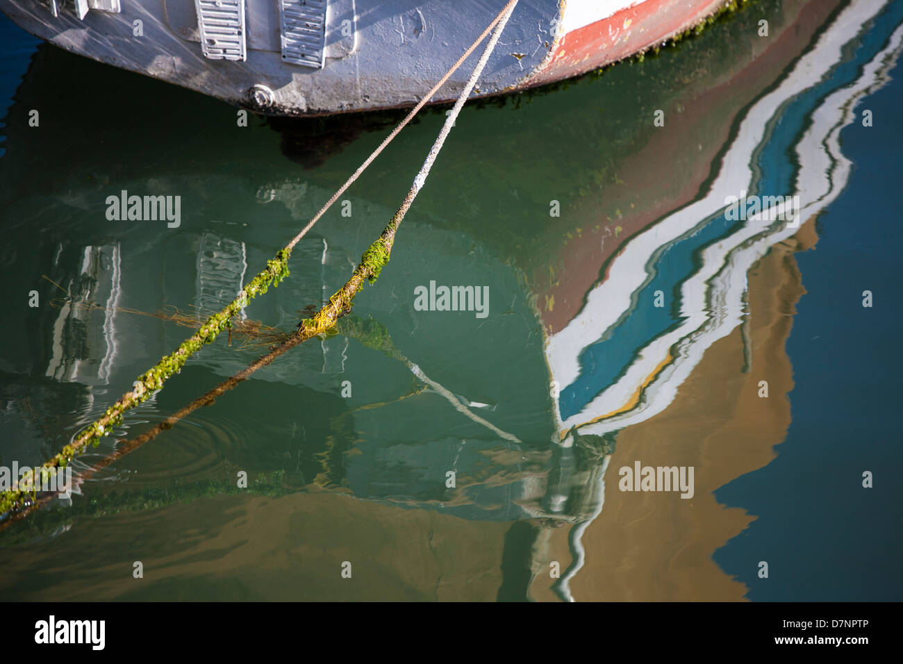 Boat reflection and a rope anchor it to the pier Stock Photo - Alamy