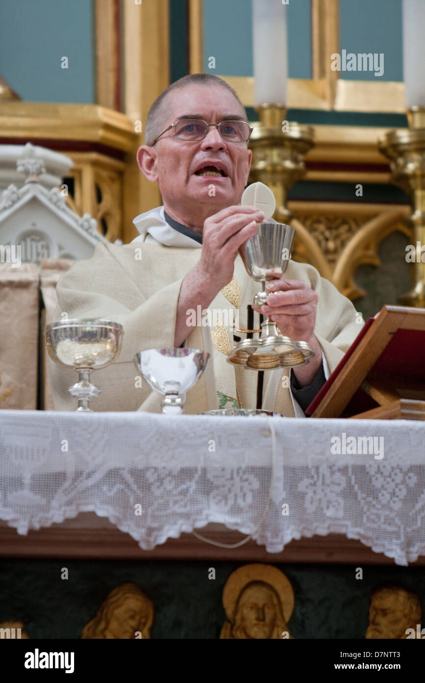 A Catholic priest celebrates mass with the Holy Eucharist and chalice Stock Photo