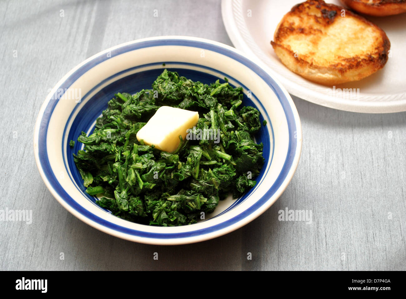 Bowl of Cooked Spinach with a Pad of Butter Stock Photo