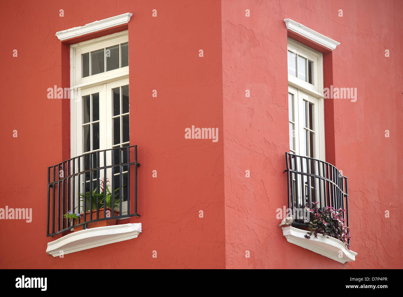 Architecture detail: Old worn white windows a red stucco building. Corner of the building. Located in San Juan, Puerto Rico. Stock Photo