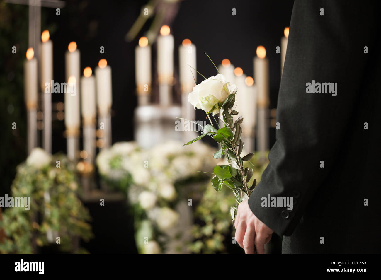 Religion, death and dolor - man at funeral with white rose mourning the dead Stock Photo