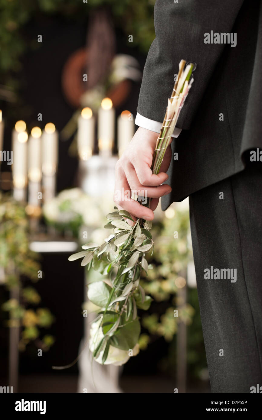 Religion, death and dolor - man at funeral with white rose mourning the dead Stock Photo