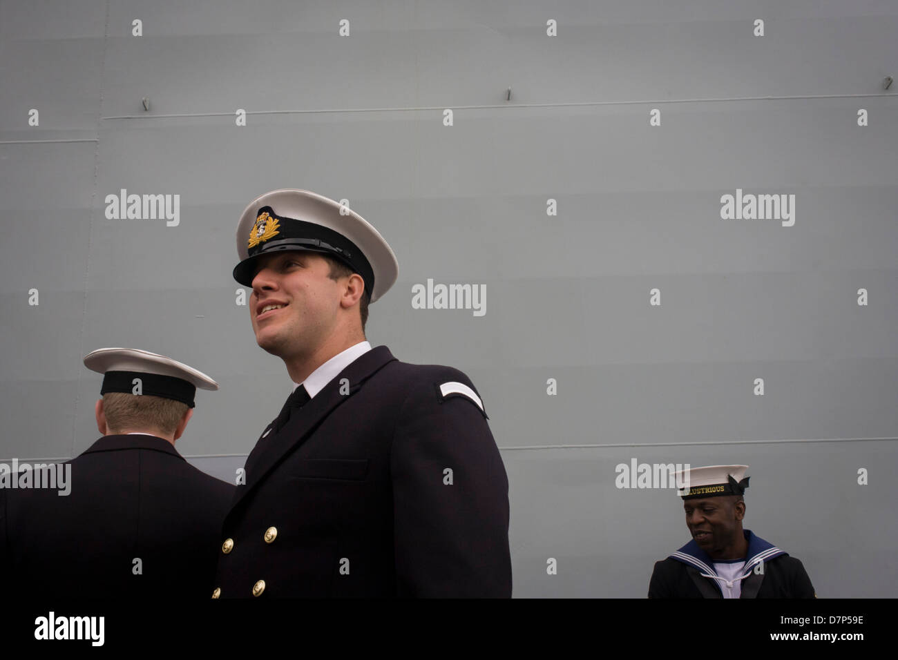 Student officers and a sailor rating on duty beneath the giant hull of ...