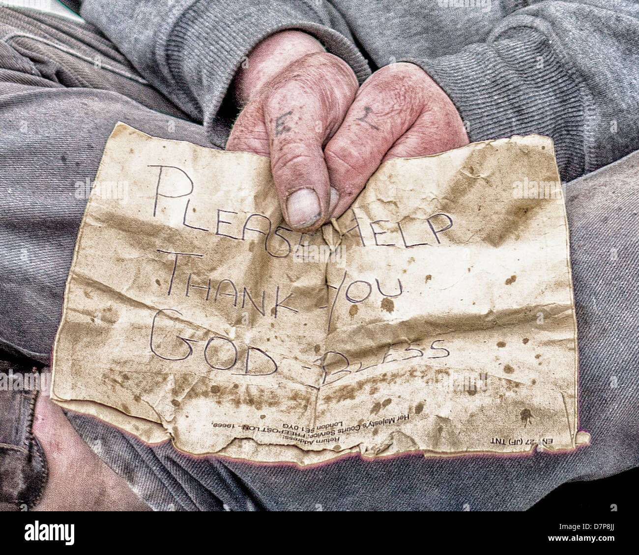 A homeless man begging in London asks for help via a message written on the back of a brown envelope. Stock Photo