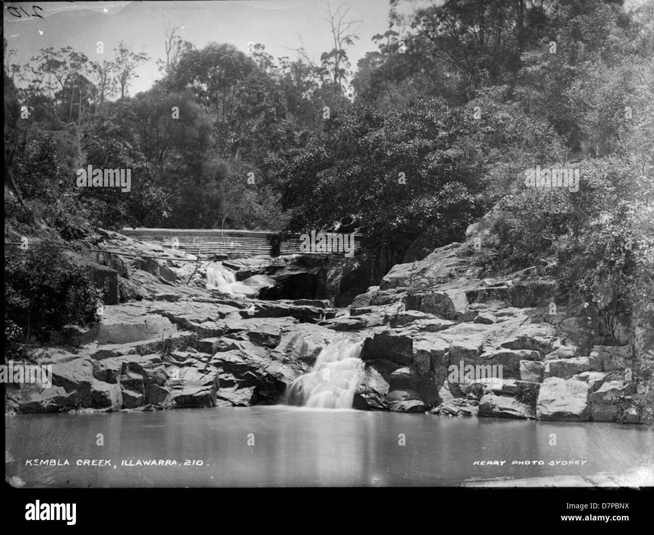 This photograph, captured by Charles H. Kerry in the Illawarra region, shows Kembla Creek, offering a picturesque view of the creek, rocks, and surrounding natural landscape. Kerry's photography captures the beauty of rural Australia. Stock Photo