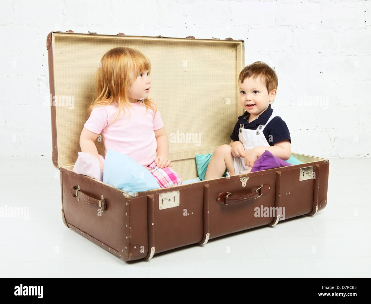 little boy and girl sitting in suitcase and playing Stock Photo