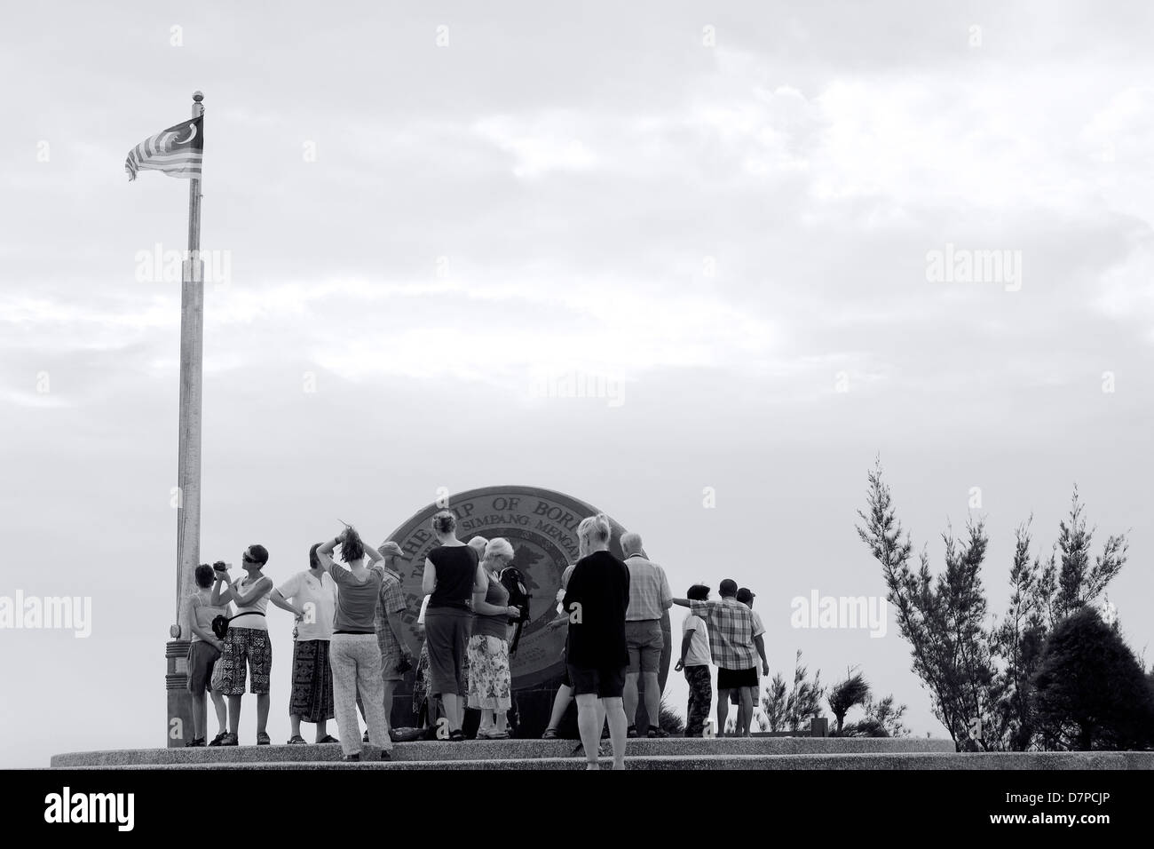 SABAH STATE, EAST MALAYSIA OCTOBER 1 2009: A group of tourists snap photos of the Globe Statue at the Tip of Borneo island. Stock Photo