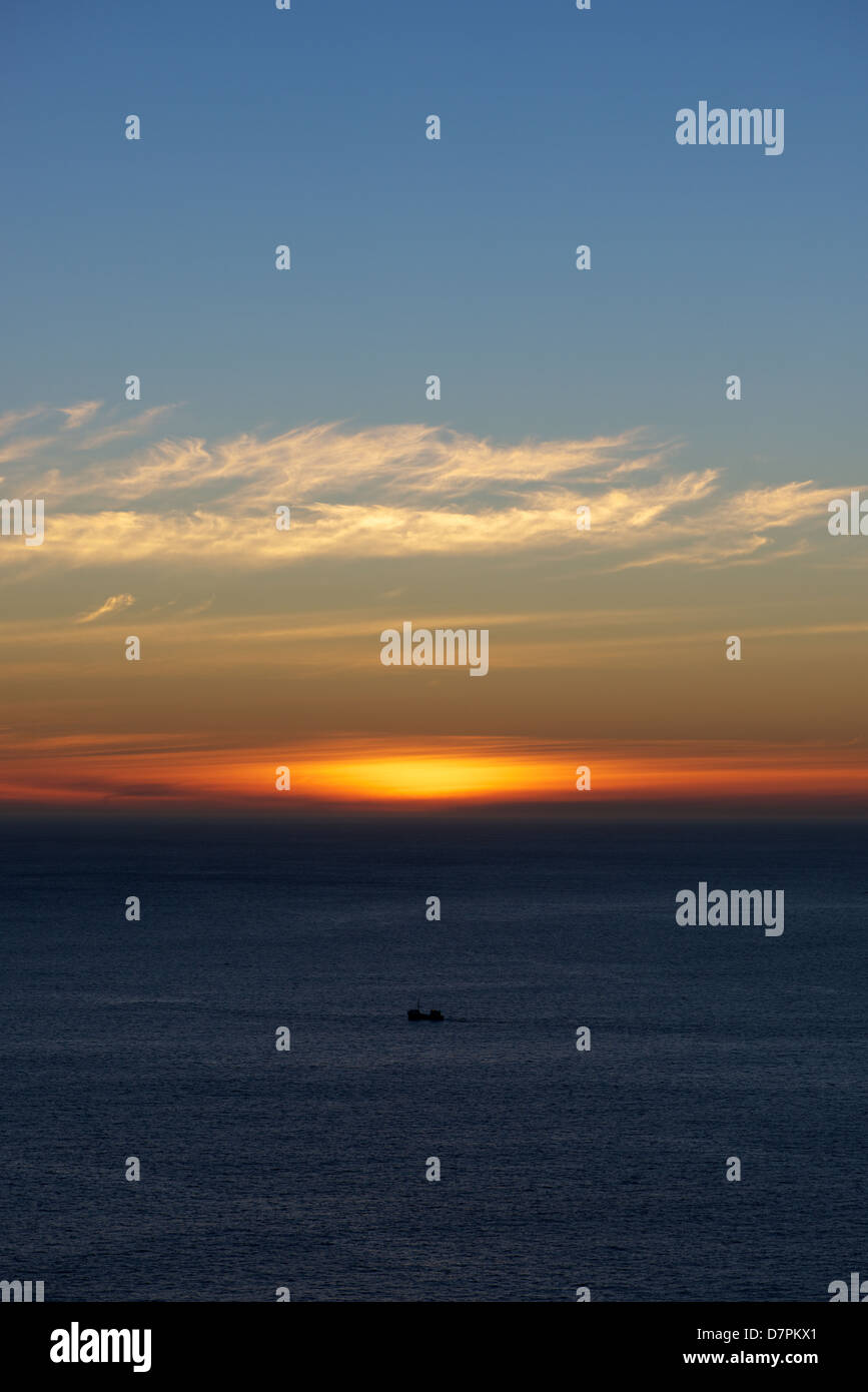 Sunset over the ocean with boat Stock Photo - Alamy
