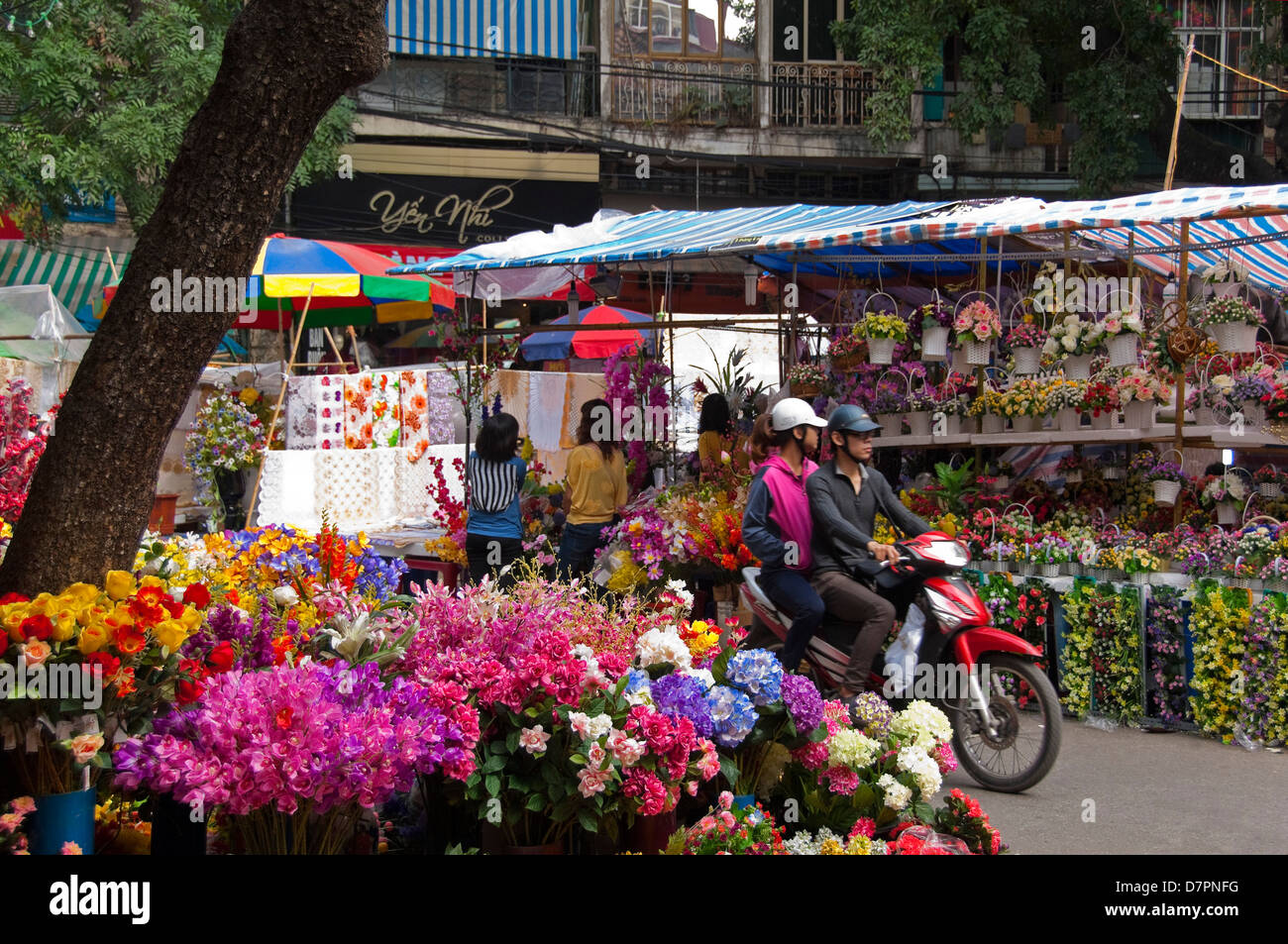Horizontal close up of the colourful flower market stalls selling arrangements in baskets and bouquets for Tet, Vietnamese New Year. Stock Photo