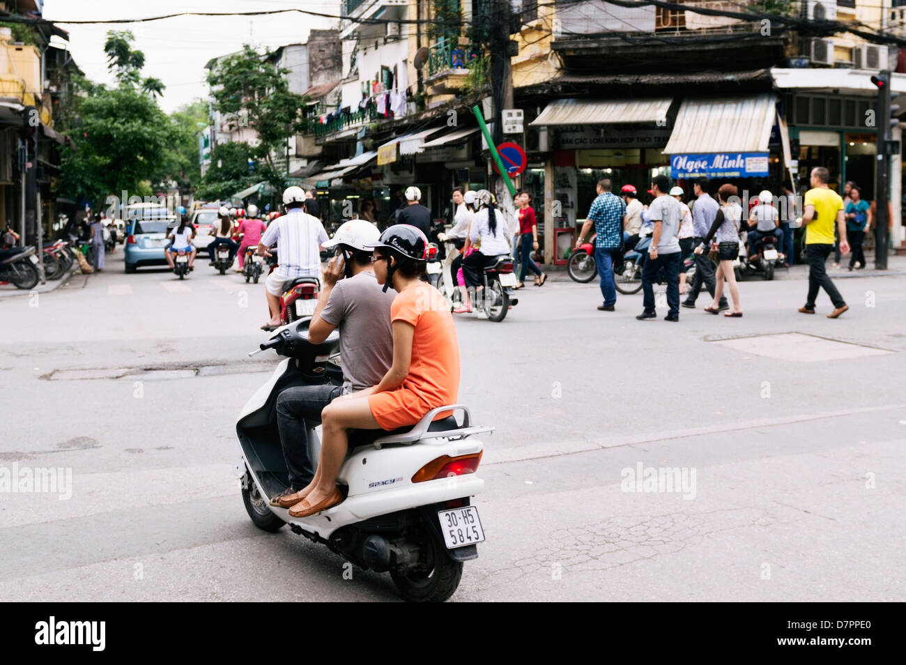 Hanoi, Vietnam young couple riding Honda motor scooter in Old Quarter he is using his
