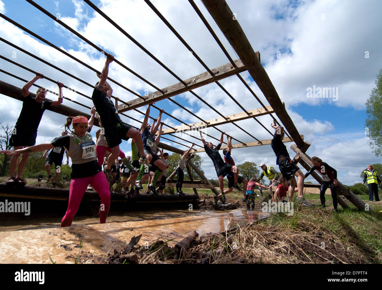 Unable to hold on a female runner drops into the muddy water as the Monkey Bars proved to be one of the most difficult obstacle Stock Photo