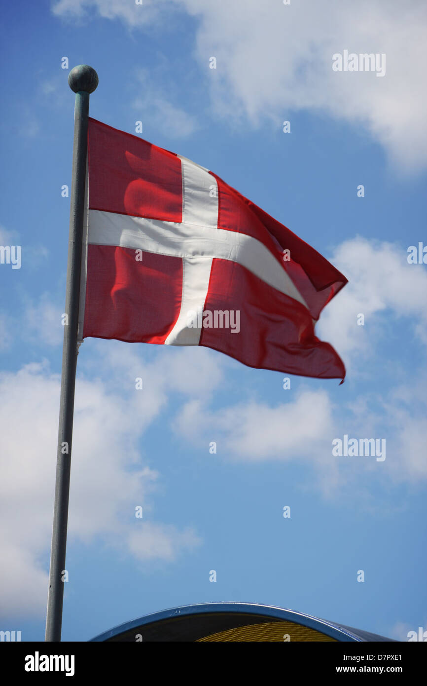 The Denmark flag waving on the wind against blue sky with white clouds Stock Photo