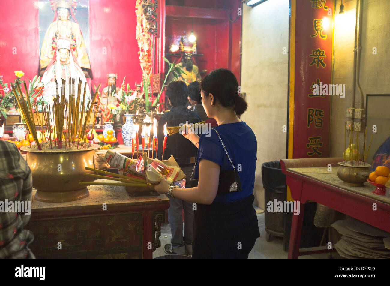 dh Man Mo temple SHEUNG WAN HONG KONG Man mo temple girl lighting joss stick chinese temple shrine offering religion woman incense china taoist scene Stock Photo