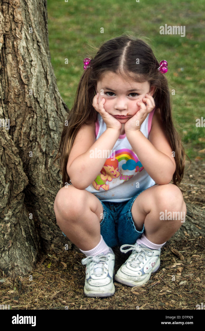 Young child pouting, squatting next to tree Stock Photo - Alamy