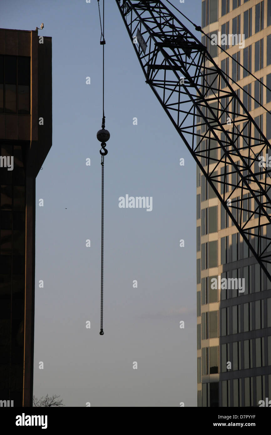 Construction crane erecting new skyscraper with cityscape backdrop Stock Photo