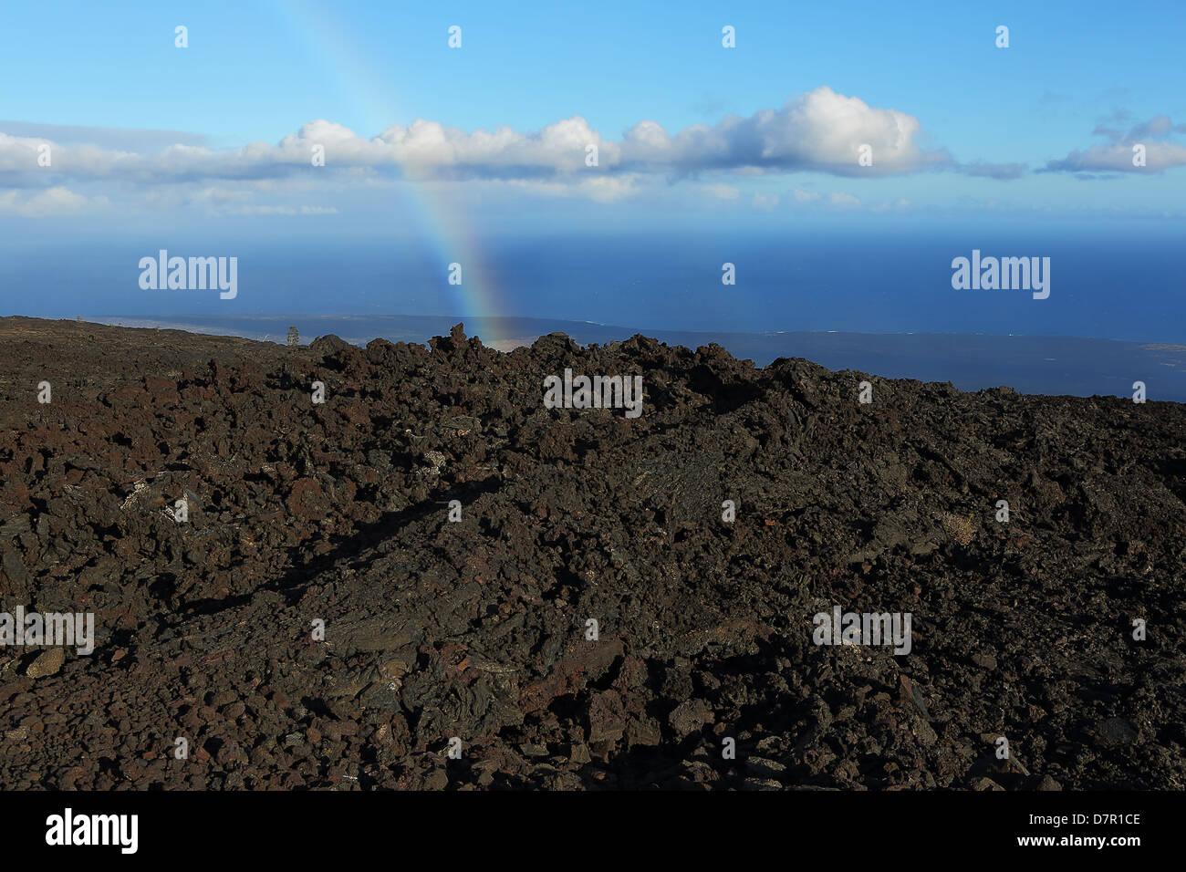 A rainbow over the fields of lava flows that extend all the way to the ocean on the big island of Hawaii Stock Photo