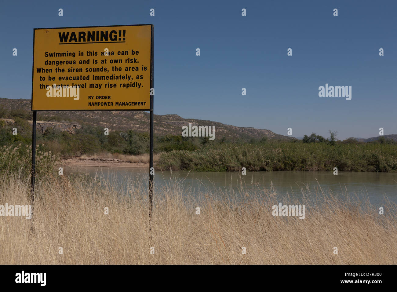 river with big yellow sign prohibiting swimming Stock Photo