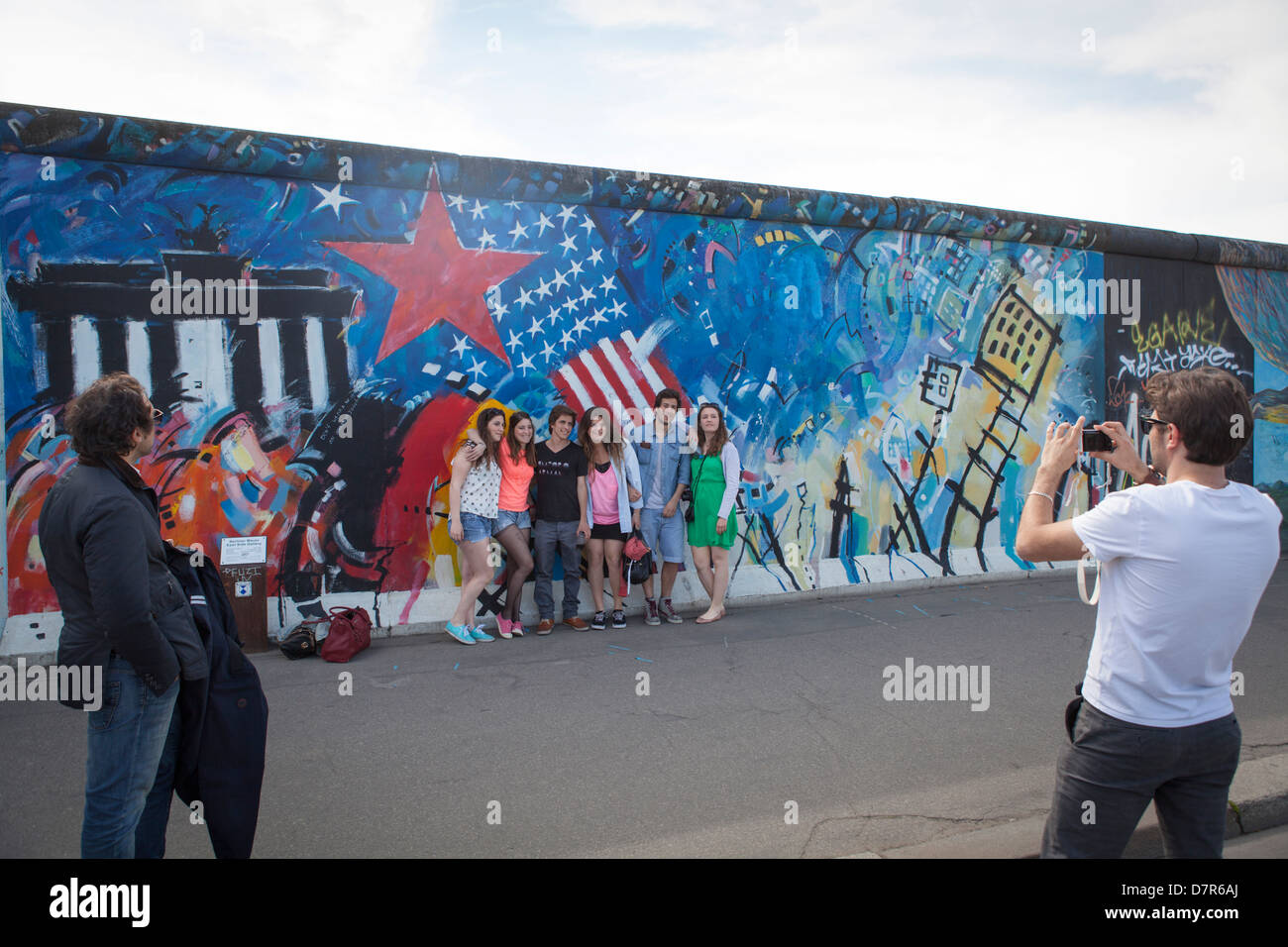Young people posing in front of the Berlin wall at Friedrichshain Stock Photo