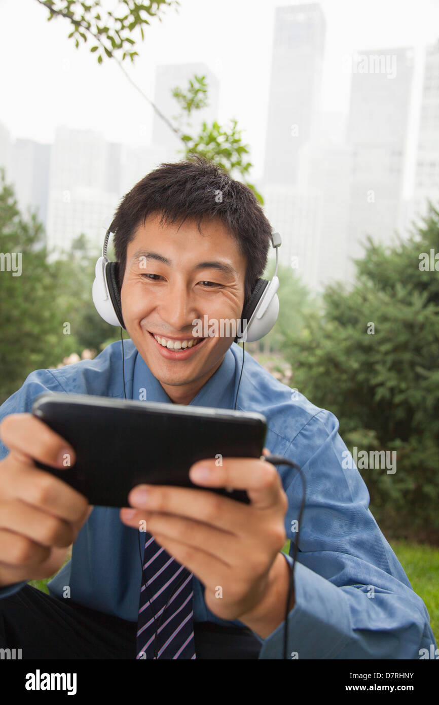 Young businessman listening to music on his MP4 player Stock Photo