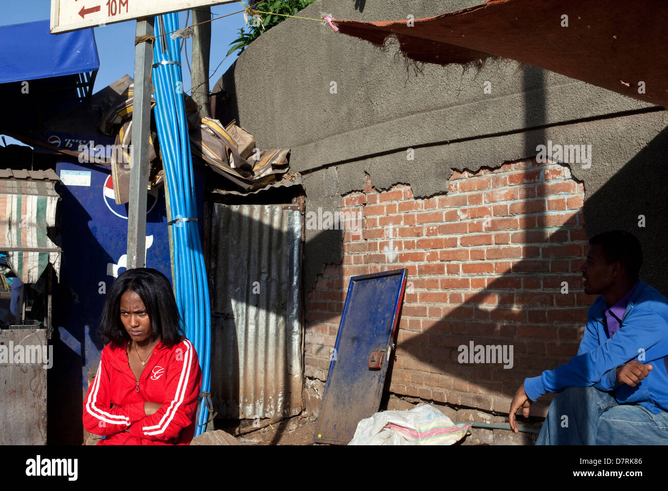 A woman in a red tracksuit waits on a street corner in the Piazza district, Addis Ababa, Ethiopia. Stock Photo