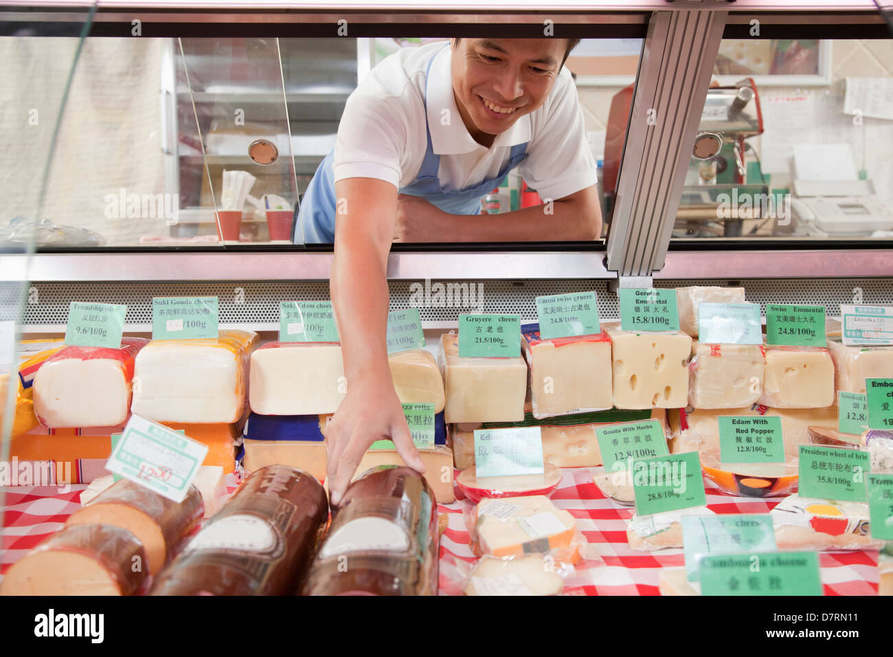 Sales Clerk reaching in to get cheese at Deli counter Stock Photo Alamy