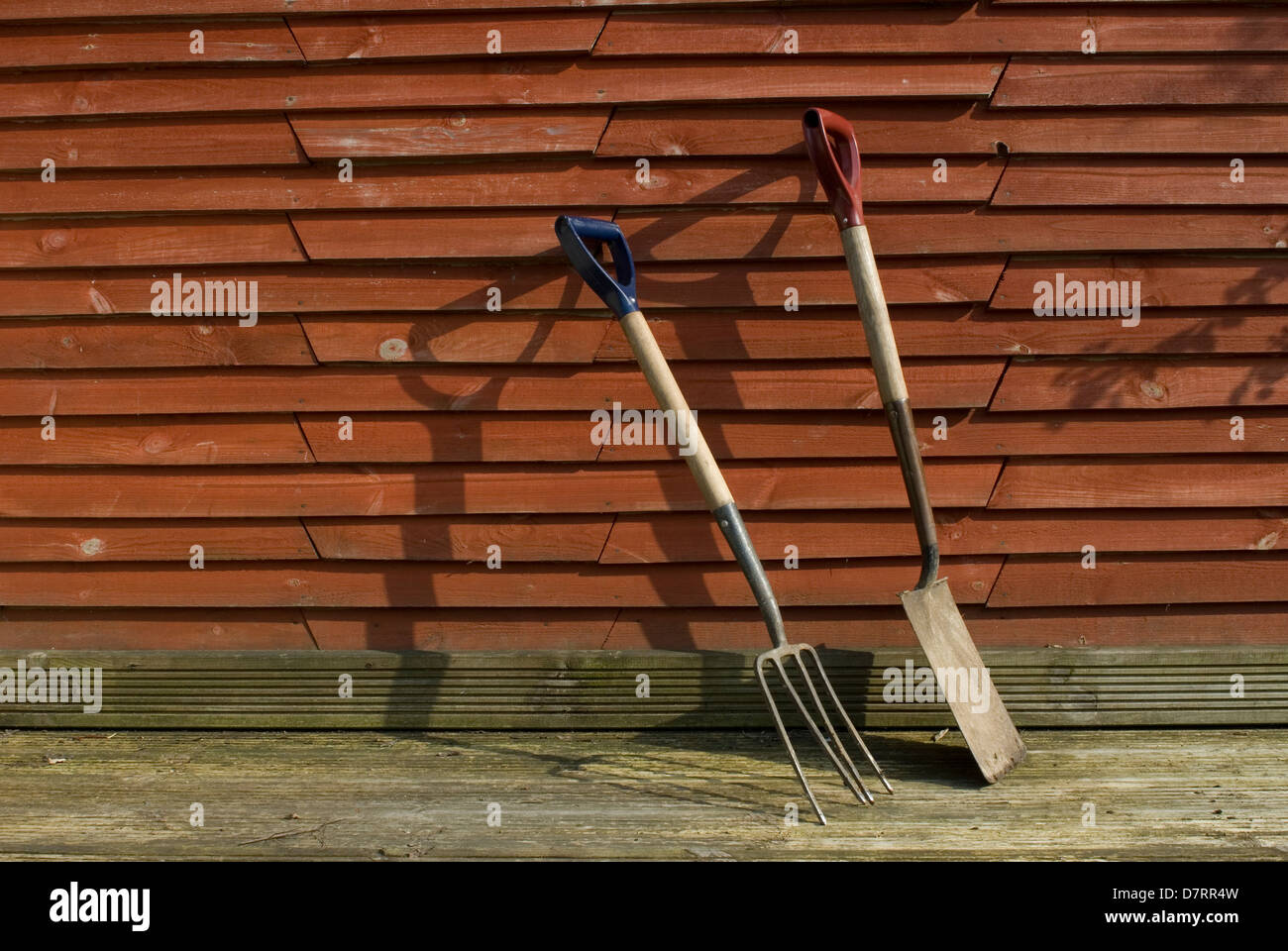 Garden fork and spade leaning on fence work hires stock photography