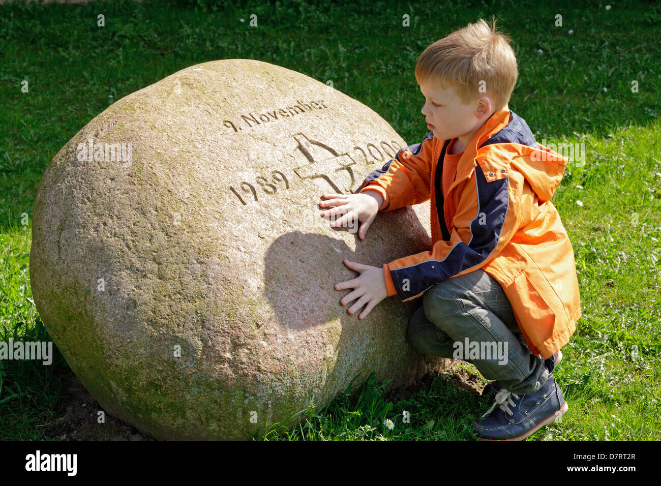 young boy looking at a memorial stone commemorating Reunification, Zarrentin, Mecklenburg-West Pomerania, Germany Stock Photo