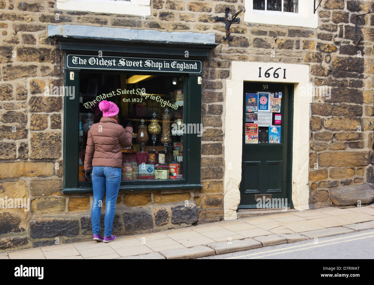 Pately Bridge, North Yorkshire, England. Girl looking in window of the Oldest Sweet Shop in England, founded in 1827. Stock Photo