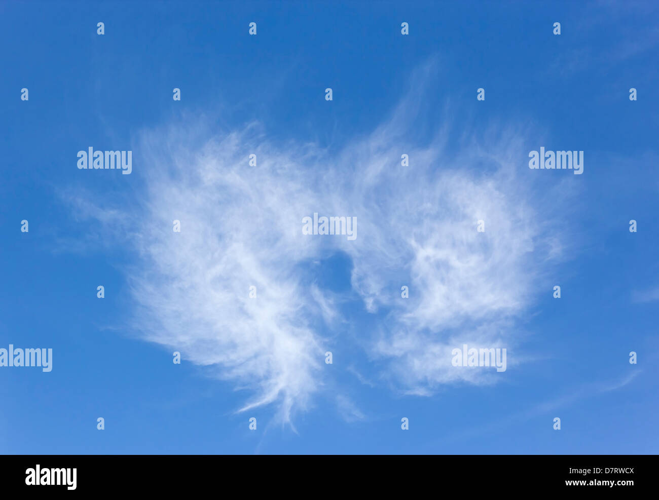 White cloud in the shape of a heart or angel's wings in bright blue sky. Stock Photo