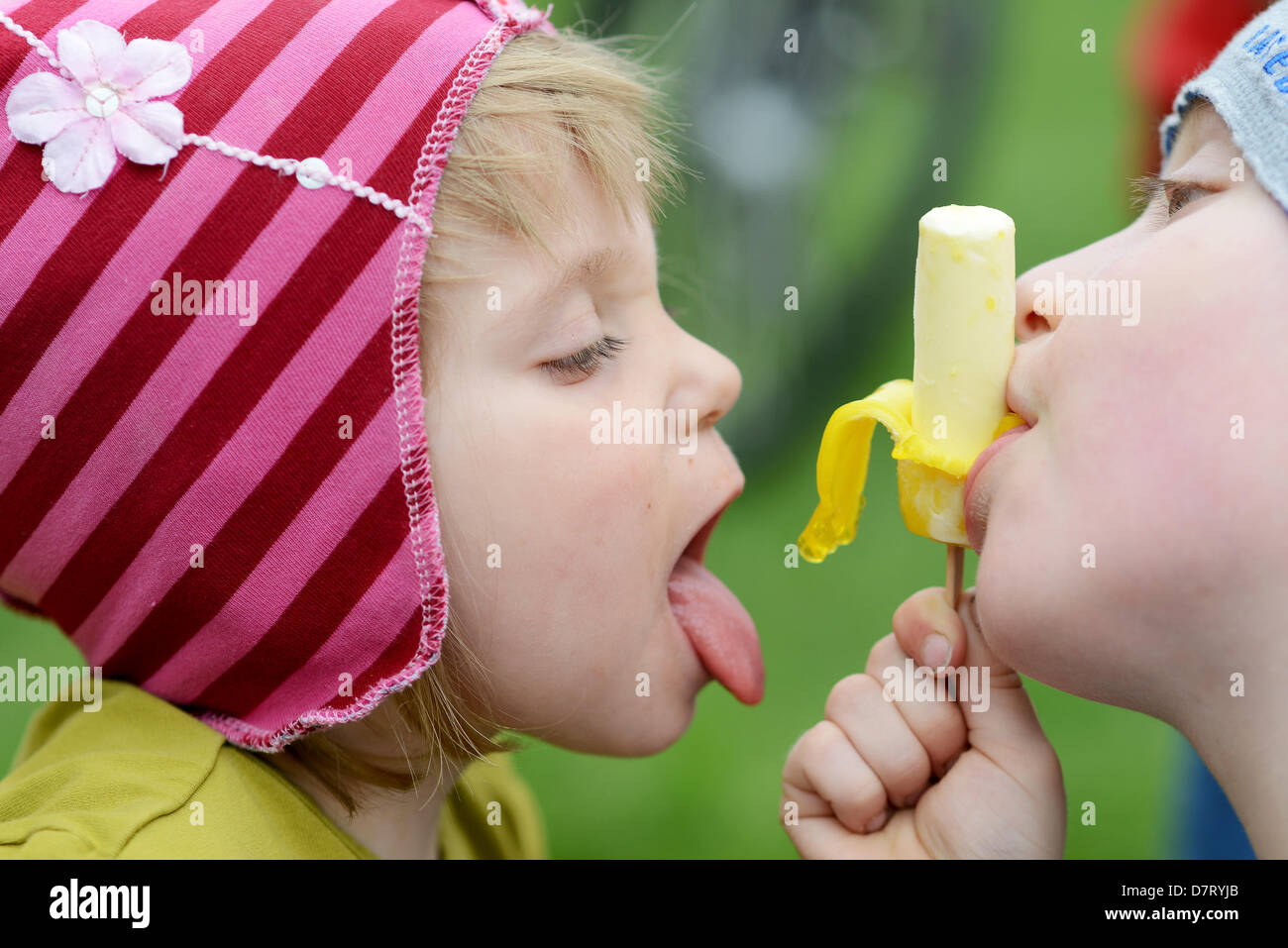 Young Frieda (L) and her brother Theo eat a banana-shaped ice cream at municipal park Hain in Bamberg, Germany, 09 May 2013. Photo: David Ebener Stock Photo