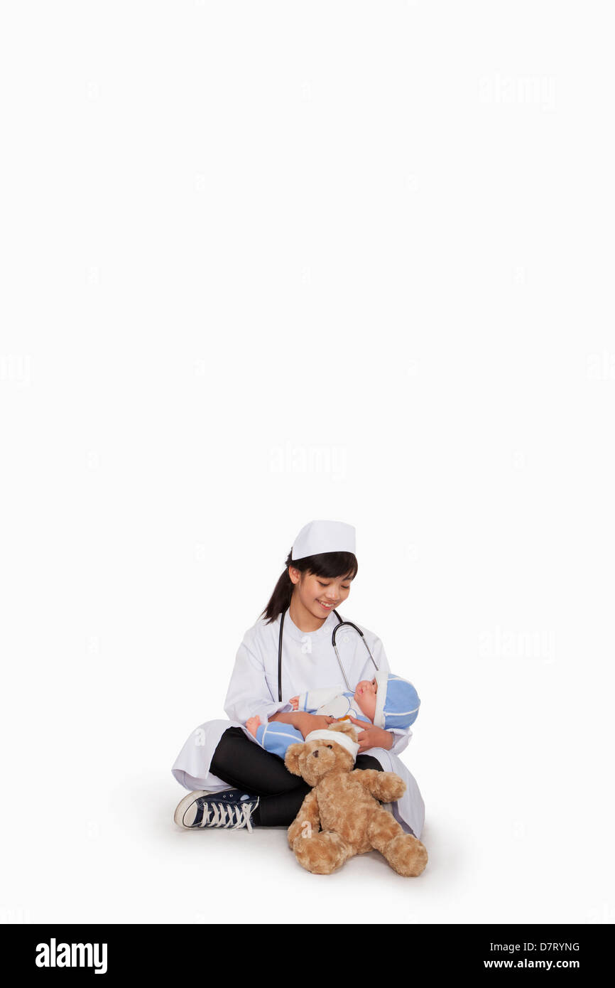 Girl dressed up as doctor with teddy bear and doll Stock Photo