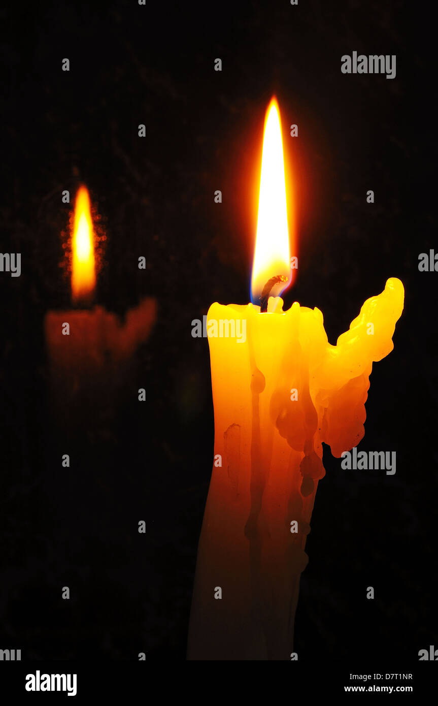 White candle with wax running down side of candle with reflection