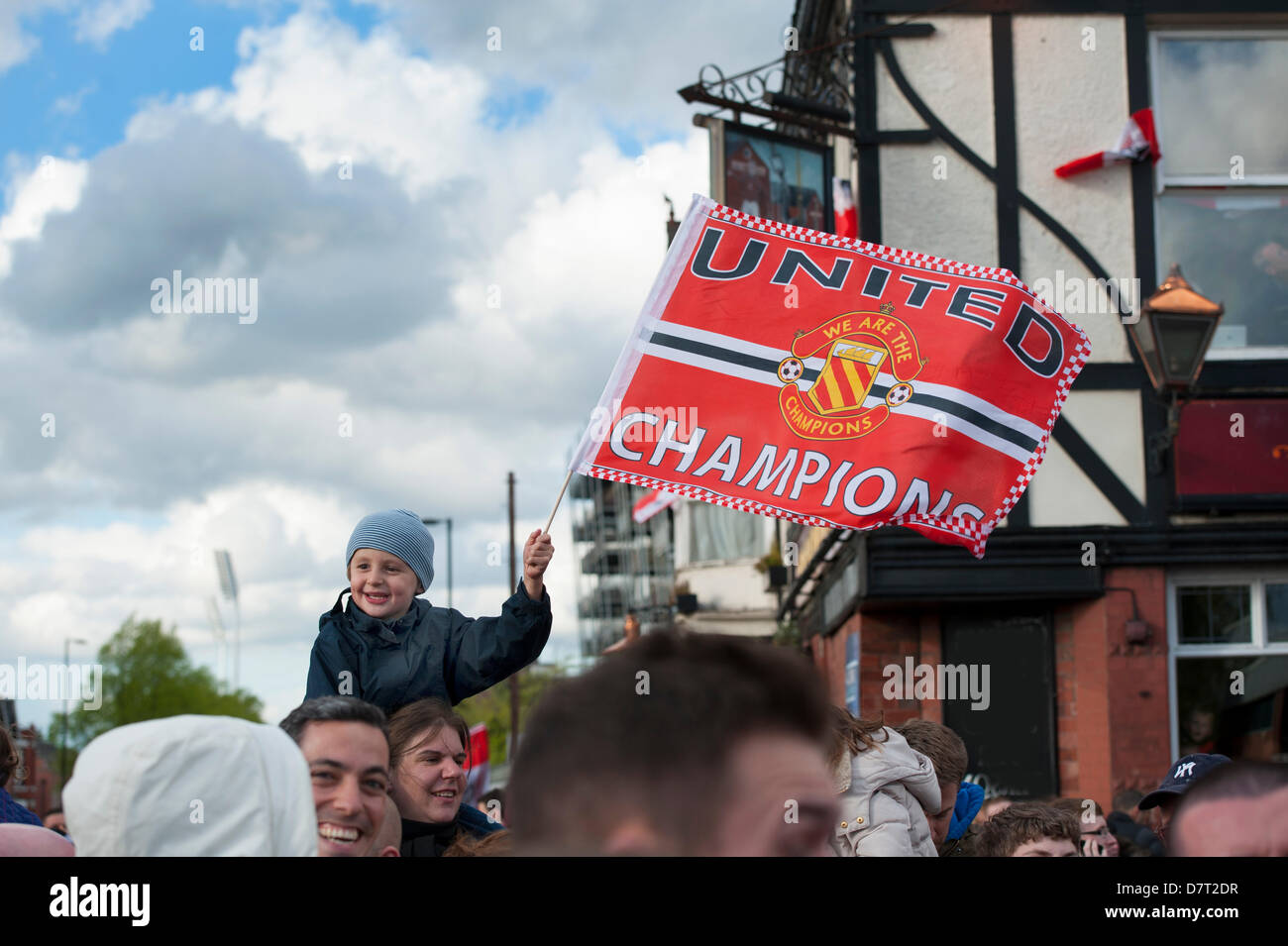 boy holds aloft a manchester united champions flag at the victory parade for the 20th league trophy in 2013 manchester england Stock Photo