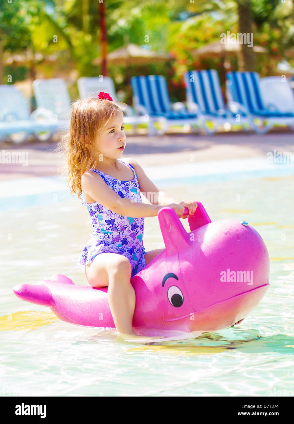 Cute little girl floating in aquapark, having fun in poolside in daycare, summer holidays, water