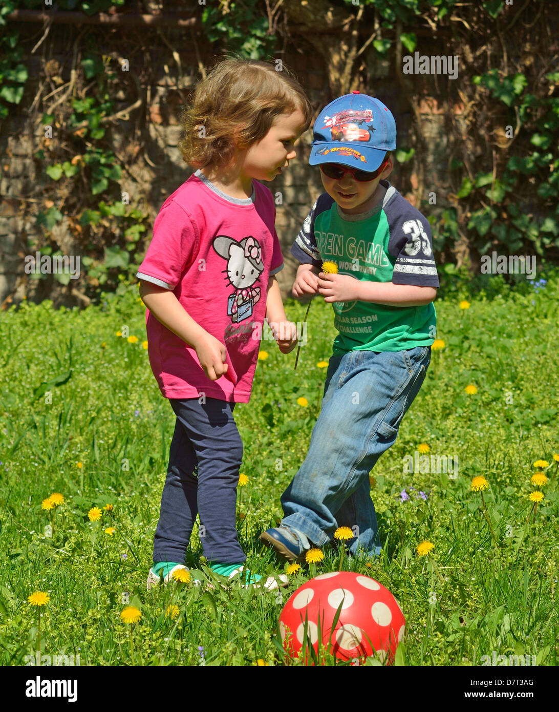 4 year old little boy and girl playing on the backyard with red ball outside Stock Photo