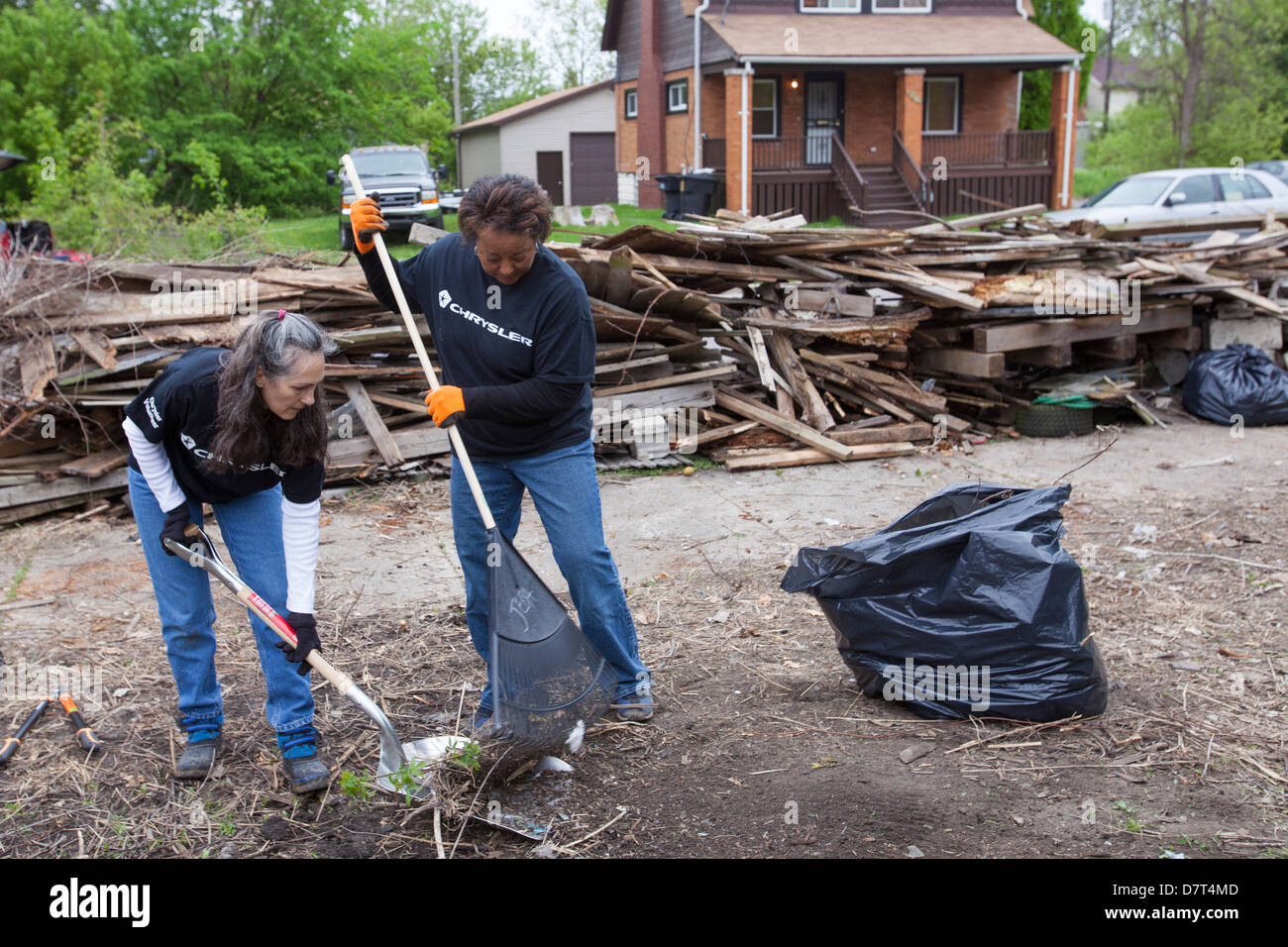 Volunteers from Chrysler Corp. and the Creekside neighborhood clean debris from vacant property in Detroit. Stock Photo
