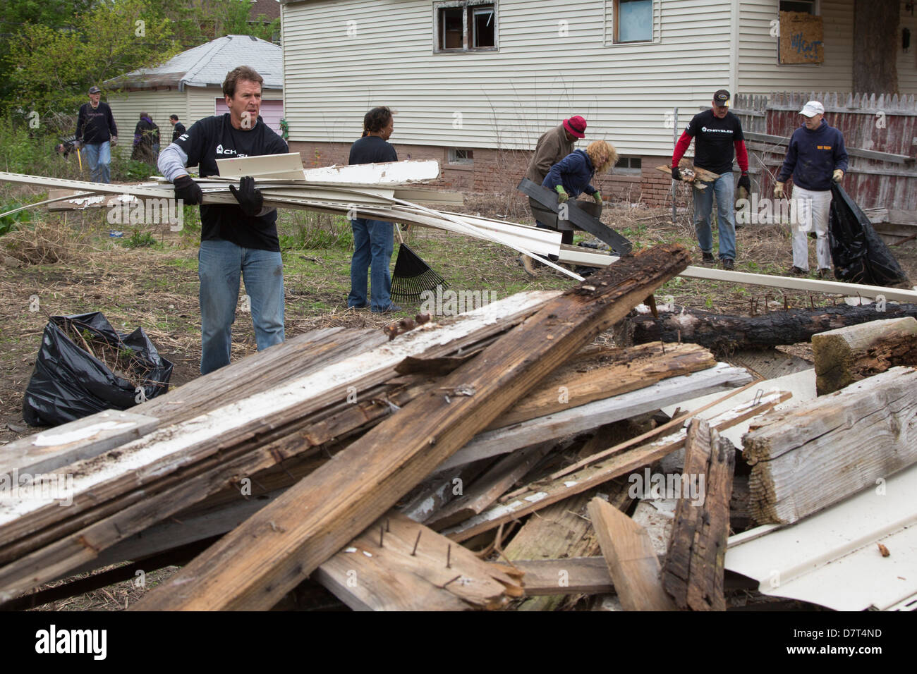 Volunteers from Chrysler Corp. and the Creekside neighborhood clean debris from vacant property in Detroit. Stock Photo