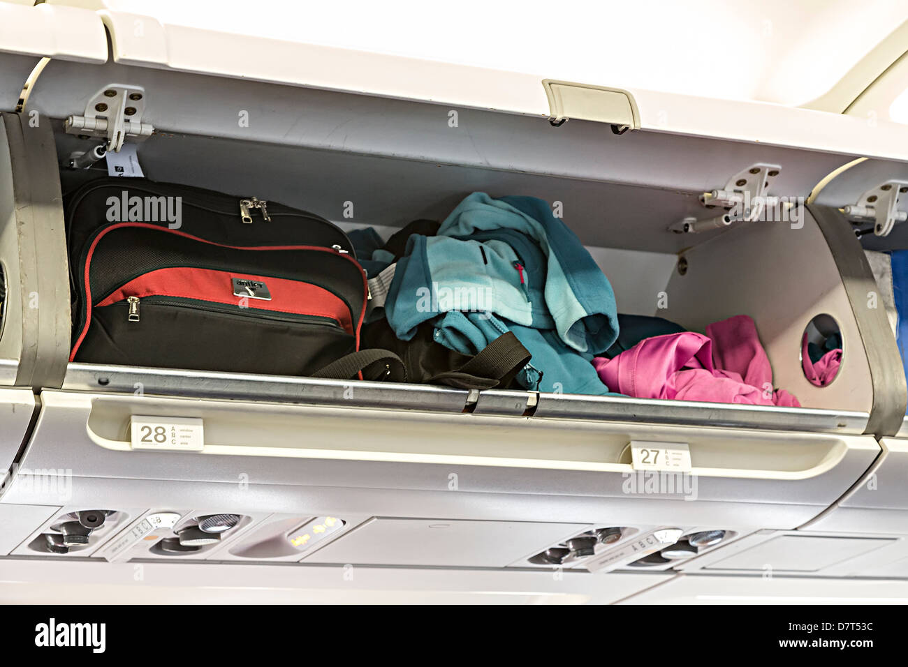 Bags and coats in an overhead locker on an aircraft preparing for flight, Spain Stock Photo