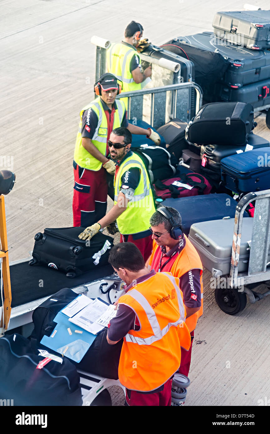 Swissport baggage handlers loading luggage into hold using conveyor belt to aircraft Lanzarote Spain Stock Photo