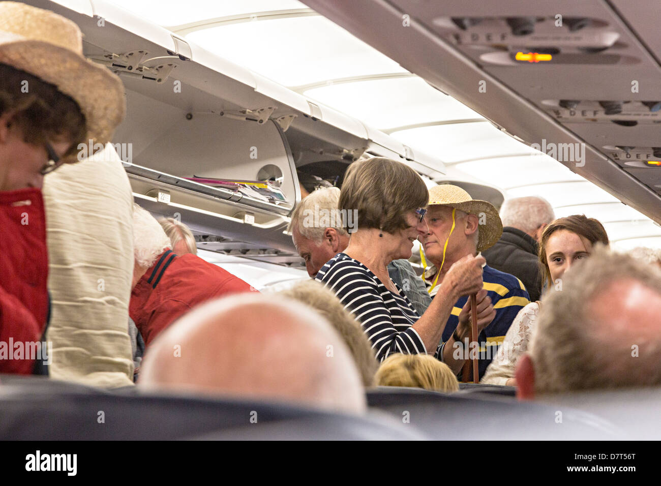 Crush of people on aircraft standing while waiting to disembark, Bristol, UK Stock Photo