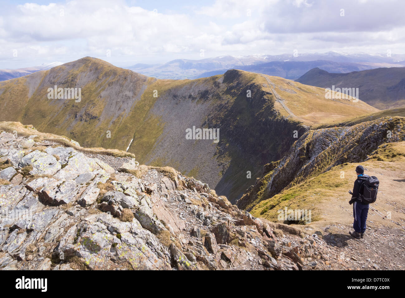 Hiker taking in the view of Hobcarton valley from Hopegill Head with Grisedale Pike in the distance. The Lake District. Stock Photo