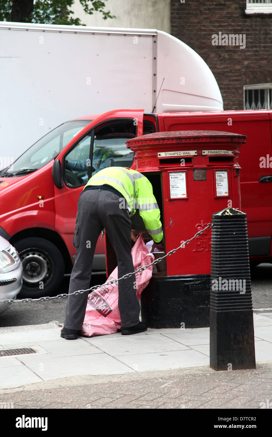 British postman collecting the mail from a letter box in paddington British postman collecting the mail from a letter box in paddington