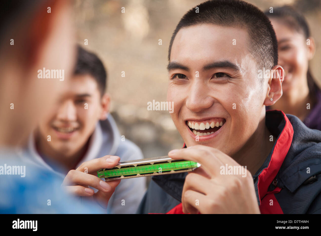 Young man using harmonica, portrait Stock Photo