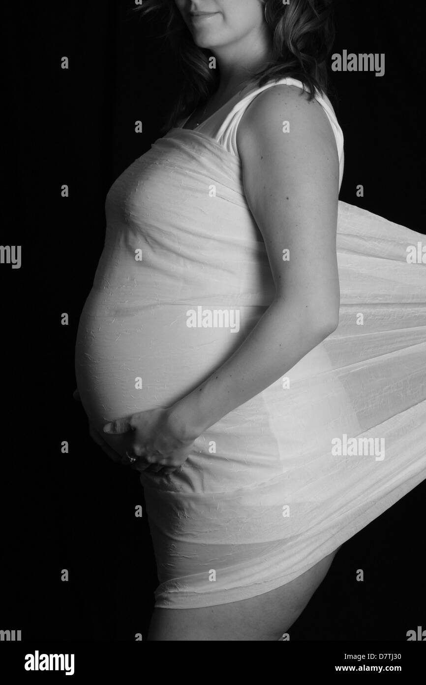 pregnant mother wrap in white cloth showing detailed curves of her belly and chest Stock Photo