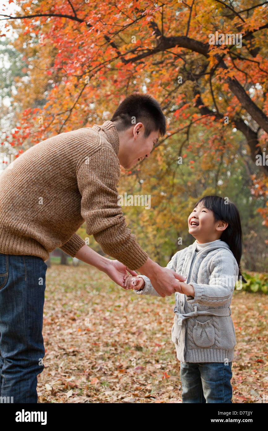 Father and daughter holding hands, looking at each other in the park ...