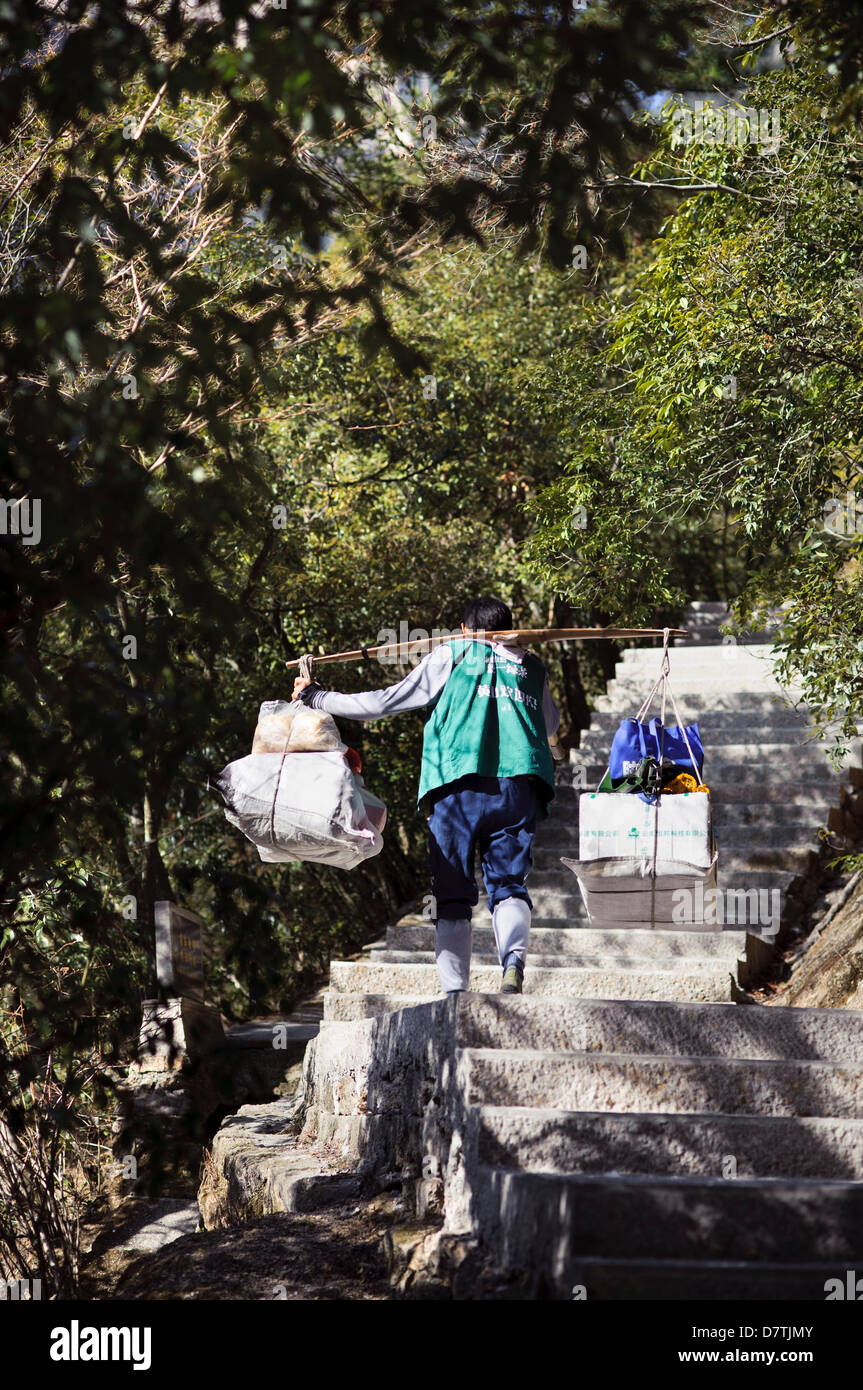 A porter carries supplies up the eastern steps of Huangshan, Anhui Province, China Stock Photo